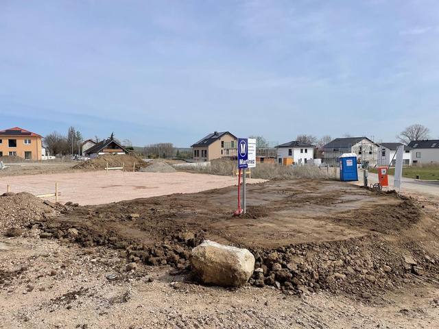 Abgeschobenes Baufeld in einem Neubaugebiet mit großem Findling im Vordergrund