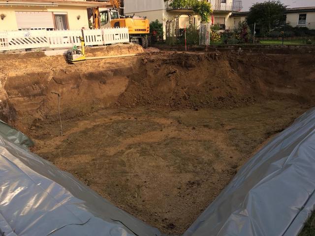 Ausgehobene Baugrube für einen Keller mit Folie an den Böschungen
