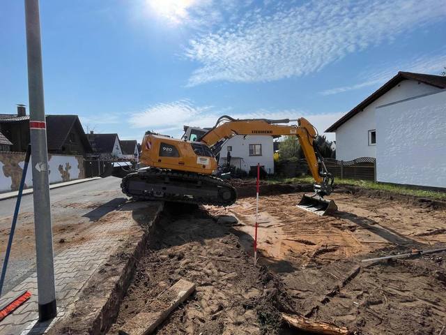 Kettenbagger hebt einen Leitungsgraben an einer Grundstücksgrenze aus